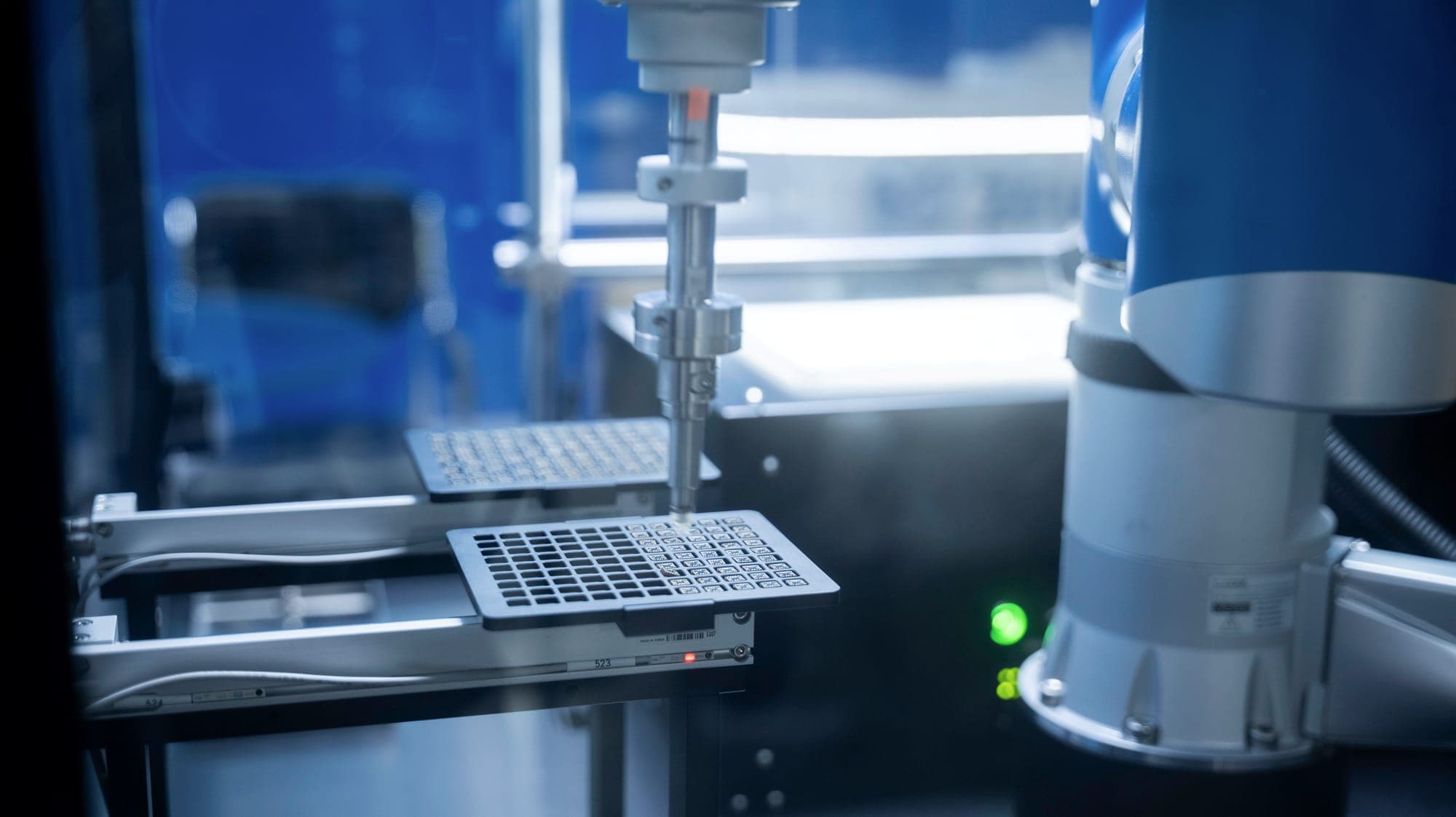 An automated pipetting head working over a well plate inside a laboratory system.