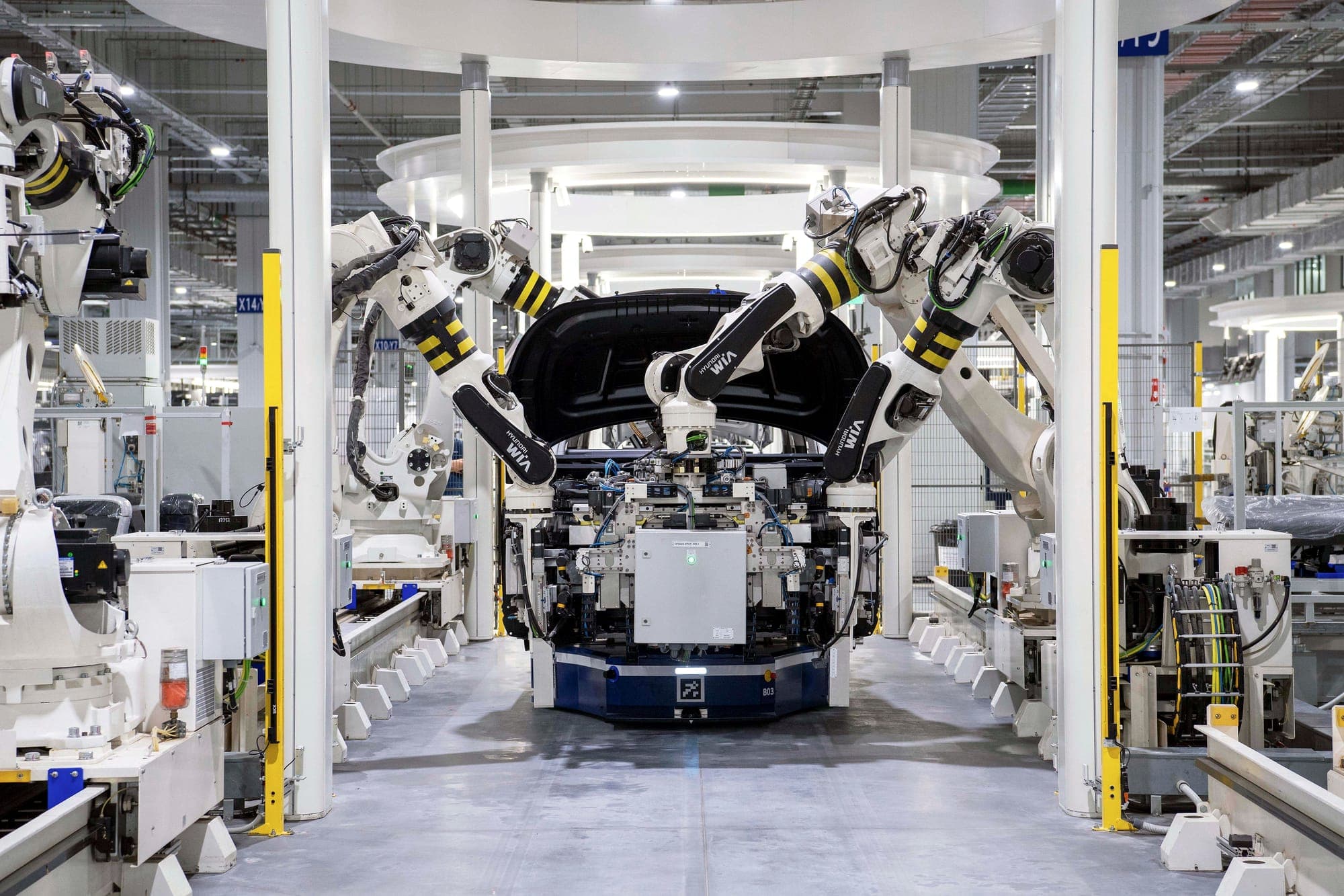 Robot arms closing in on a car body on an automated assembly line.